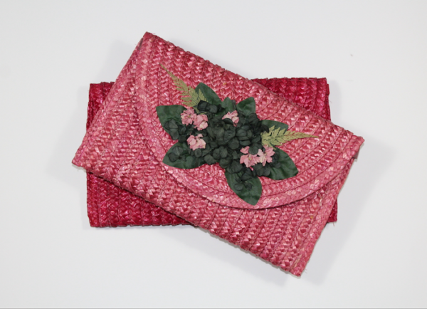 Bolso de paja rosa con decoración floral y hojas secas